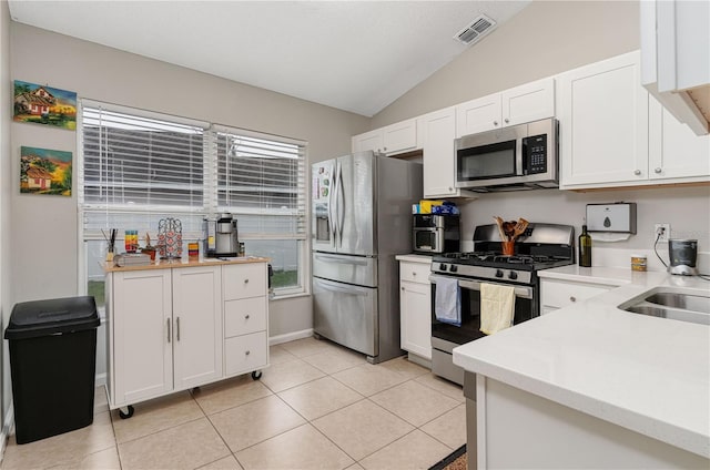 kitchen with light countertops, visible vents, appliances with stainless steel finishes, white cabinets, and vaulted ceiling