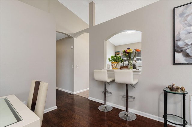 interior space with arched walkways, wood finished floors, and baseboards