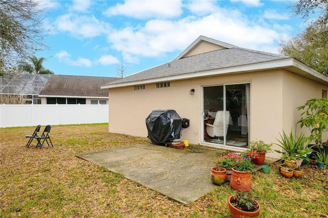 rear view of house featuring stucco siding, fence, a patio, and a lawn