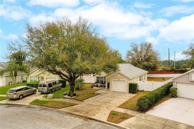 view of front of property featuring a detached garage, stucco siding, a gate, fence, and a front lawn