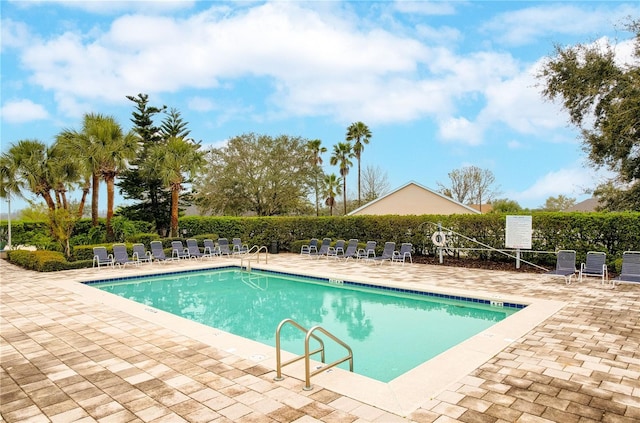 community pool with a patio area and fence