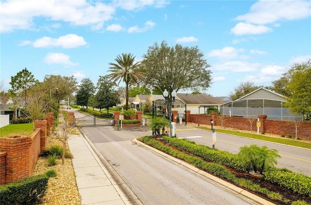 view of street with street lighting, a gate, curbs, and a gated entry