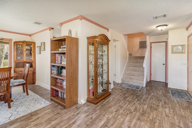 interior space with wood finished floors, visible vents, and crown molding