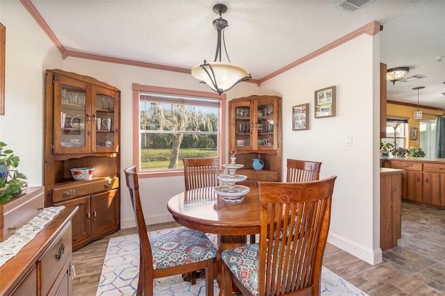 dining space featuring a textured ceiling, visible vents, baseboards, ornamental molding, and light wood-type flooring