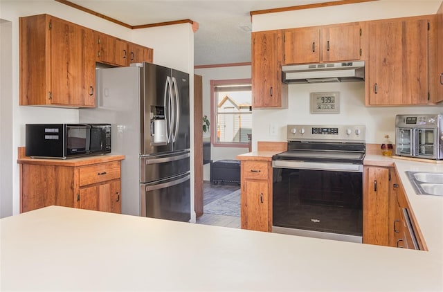 kitchen with crown molding, stainless steel appliances, light countertops, and under cabinet range hood