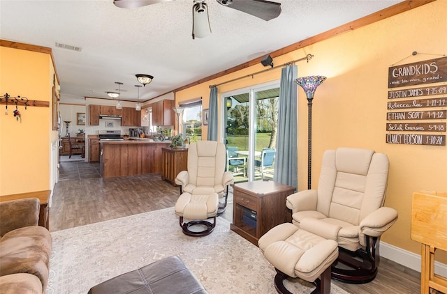 living room with dark wood-style floors, visible vents, a textured ceiling, and baseboards