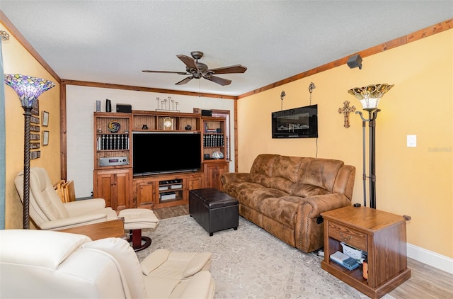 living area featuring crown molding, ceiling fan, light wood-style flooring, and a textured ceiling