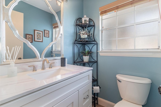 bathroom with baseboards, vanity, and toilet