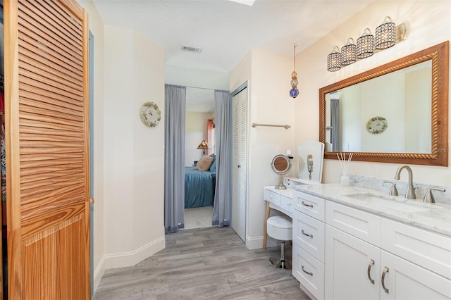 full bathroom with wood finished floors, vanity, visible vents, baseboards, and a closet