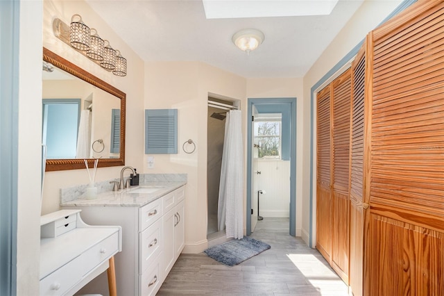 full bathroom with a shower with curtain, a closet, wood finished floors, and vanity