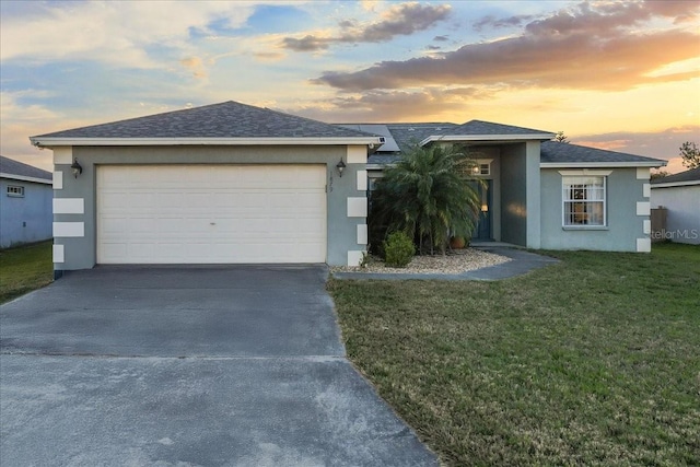 ranch-style house with stucco siding, a lawn, concrete driveway, and a shingled roof