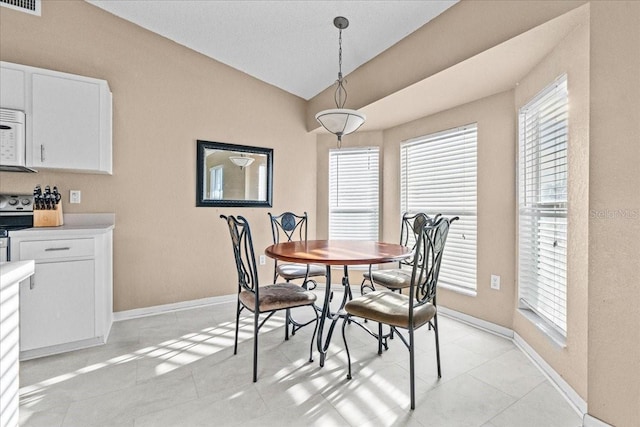 dining area with lofted ceiling, light tile patterned floors, a healthy amount of sunlight, and baseboards