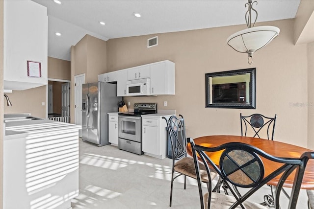 kitchen featuring visible vents, a sink, appliances with stainless steel finishes, white cabinets, and lofted ceiling