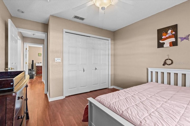 bedroom with wood finished floors, visible vents, a closet, and baseboards