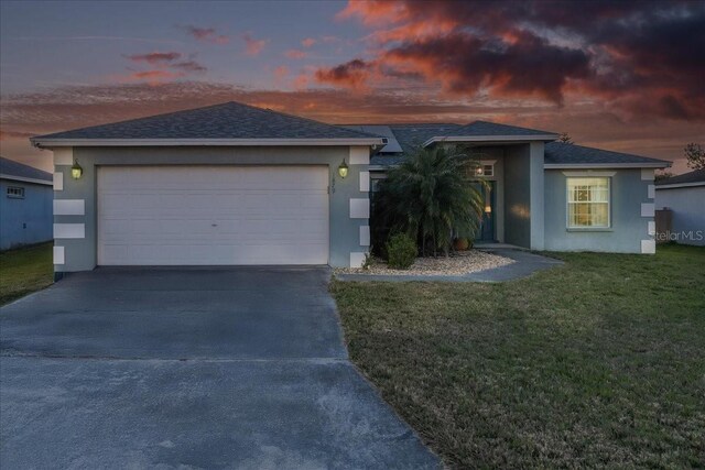 ranch-style house with a garage, stucco siding, driveway, and a front lawn