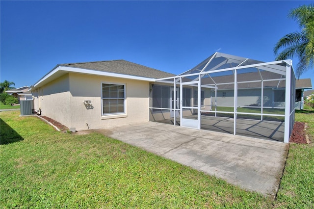 back of house with stucco siding, cooling unit, a lawn, glass enclosure, and a patio area