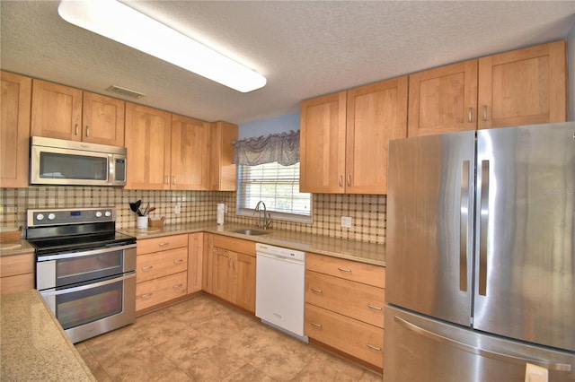 kitchen featuring visible vents, light brown cabinetry, a sink, light countertops, and appliances with stainless steel finishes