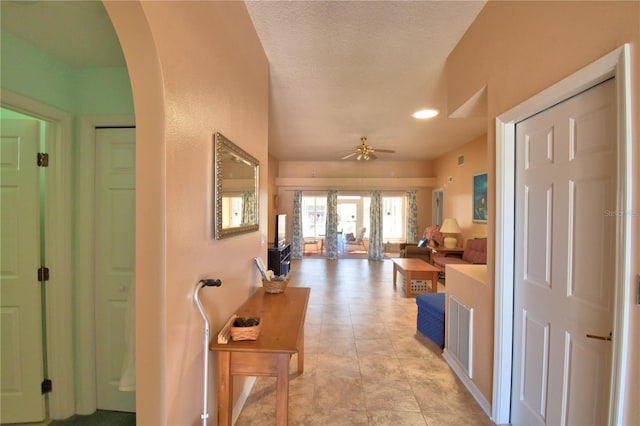 hall featuring arched walkways, recessed lighting, and a textured ceiling