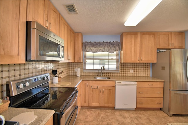 kitchen with visible vents, a sink, decorative backsplash, stainless steel appliances, and a textured ceiling