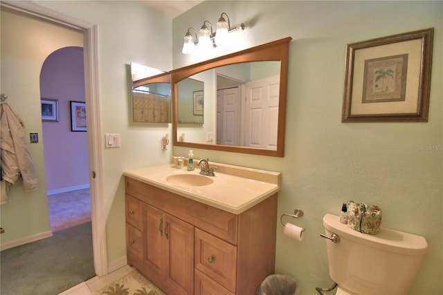 bathroom with toilet, vanity, and baseboards