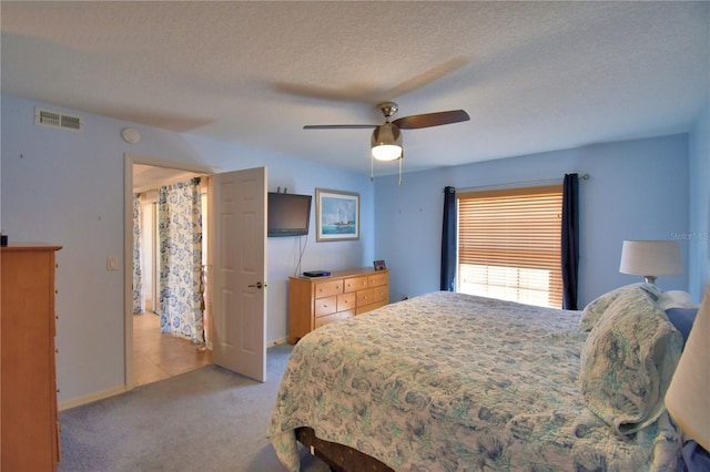 bedroom featuring visible vents, a textured ceiling, carpet floors, baseboards, and ceiling fan