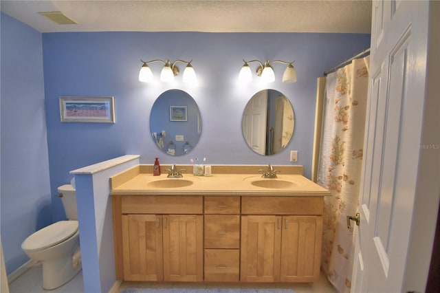 bathroom featuring a sink, visible vents, toilet, and double vanity