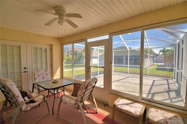 sunroom with a ceiling fan and a residential view