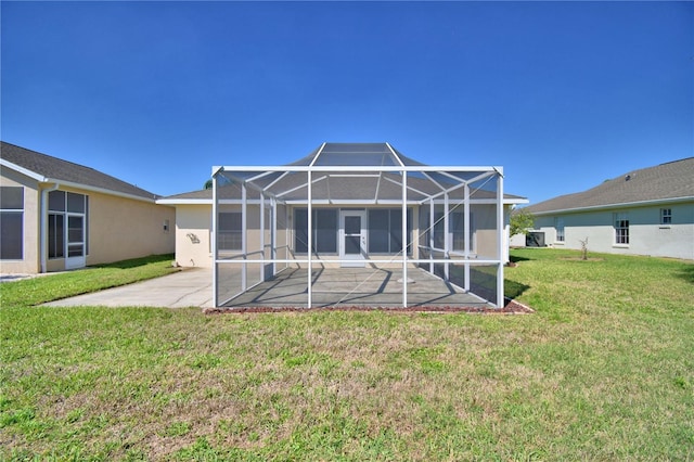 rear view of property with a lanai, a yard, a patio, and stucco siding