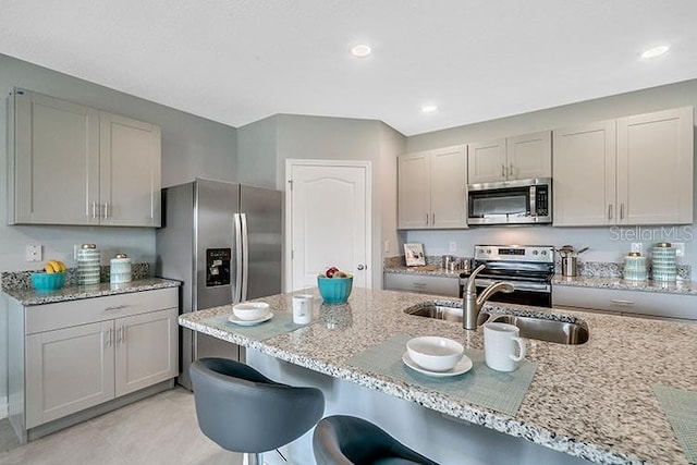 1861 Walnut Creek Dr, Kissimmee, FL 34744 - kitchen with stainless steel appliances, a sink, gray cabinets, a kitchen bar, and light stone countertops