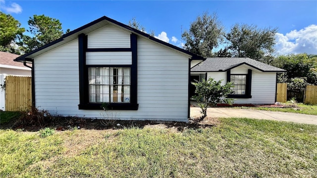 view of home's exterior with a lawn and fence