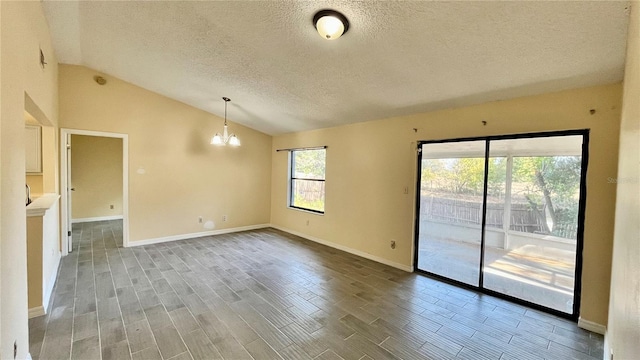 unfurnished room featuring a textured ceiling, a chandelier, wood finished floors, baseboards, and vaulted ceiling