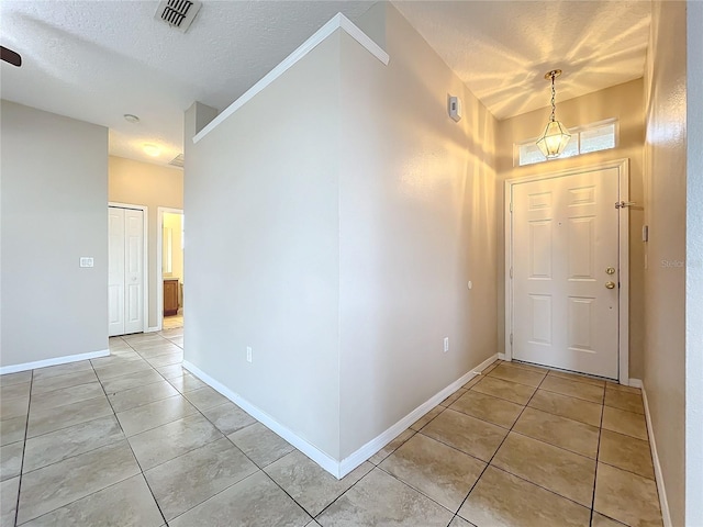 foyer featuring light tile patterned floors, visible vents, and a textured ceiling