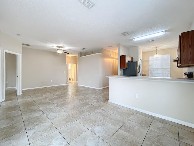 interior space featuring light tile patterned floors, visible vents, ceiling fan, a textured ceiling, and stainless steel fridge