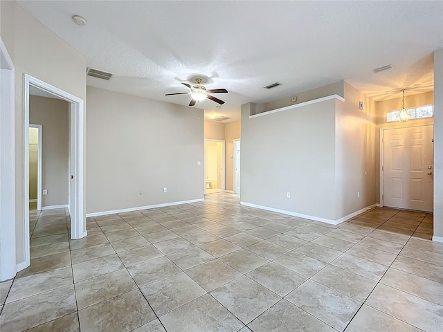 empty room with light tile patterned floors, a textured ceiling, visible vents, and a ceiling fan