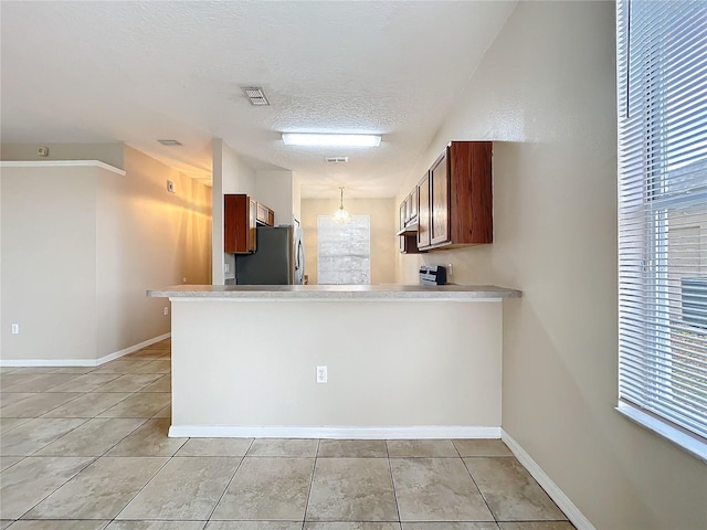 kitchen featuring light countertops, visible vents, freestanding refrigerator, a textured ceiling, and a peninsula