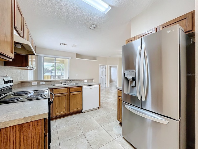 kitchen featuring white dishwasher, under cabinet range hood, range with electric cooktop, a sink, and stainless steel refrigerator with ice dispenser