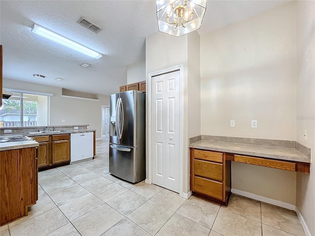 kitchen featuring visible vents, stainless steel fridge with ice dispenser, brown cabinets, white dishwasher, and a sink