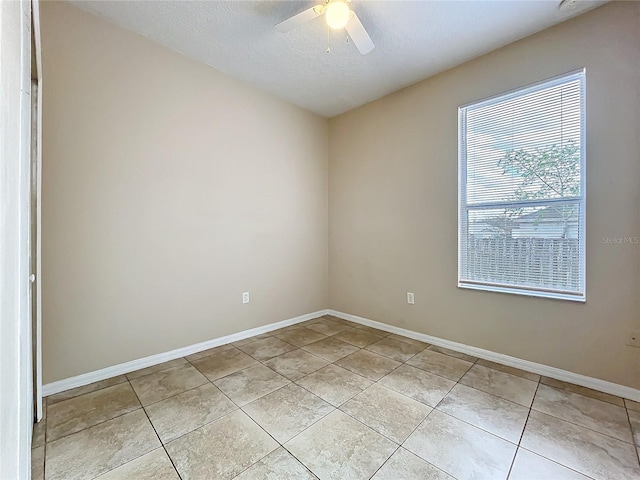 unfurnished room with light tile patterned floors, a textured ceiling, baseboards, and a ceiling fan