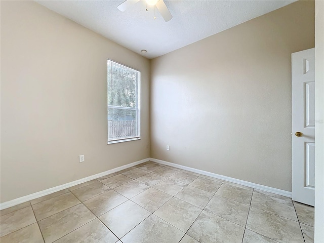 empty room featuring ceiling fan, a textured ceiling, light tile patterned flooring, and baseboards