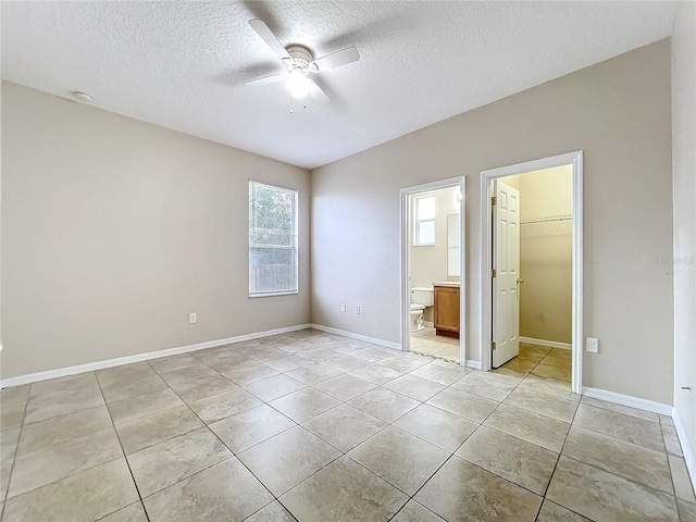 unfurnished bedroom featuring a walk in closet, a closet, light tile patterned flooring, and a textured ceiling