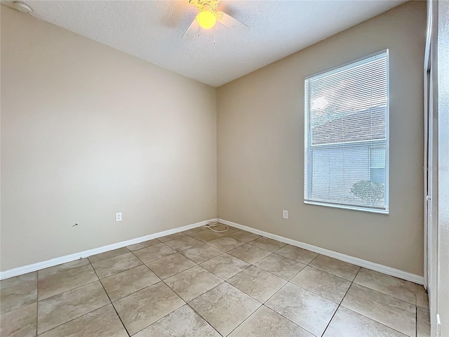 spare room featuring ceiling fan, a textured ceiling, baseboards, and light tile patterned floors