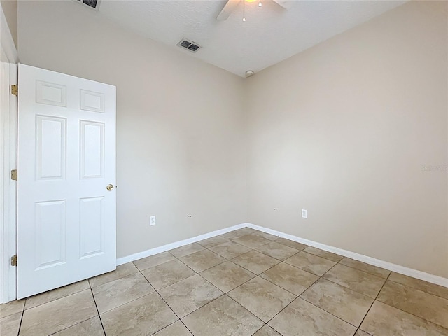 spare room with light tile patterned floors, ceiling fan, visible vents, and baseboards