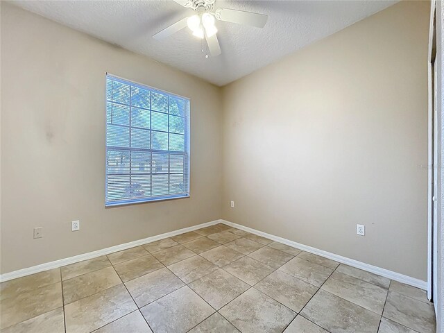 unfurnished room featuring ceiling fan, a textured ceiling, baseboards, and light tile patterned floors