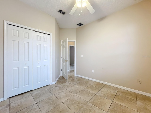 unfurnished bedroom with a textured ceiling, light tile patterned floors, a closet, and visible vents