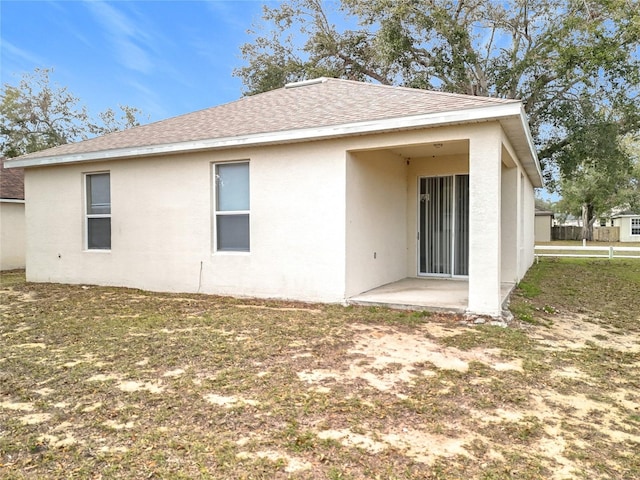 back of property with roof with shingles, a patio area, and stucco siding