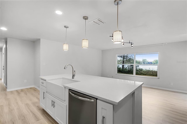 kitchen with dishwasher, light countertops, a sink, and light wood-style floors