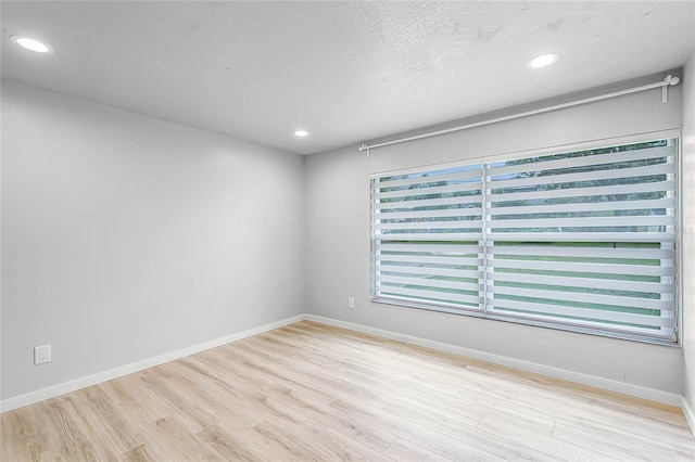 spare room featuring recessed lighting, baseboards, and wood finished floors