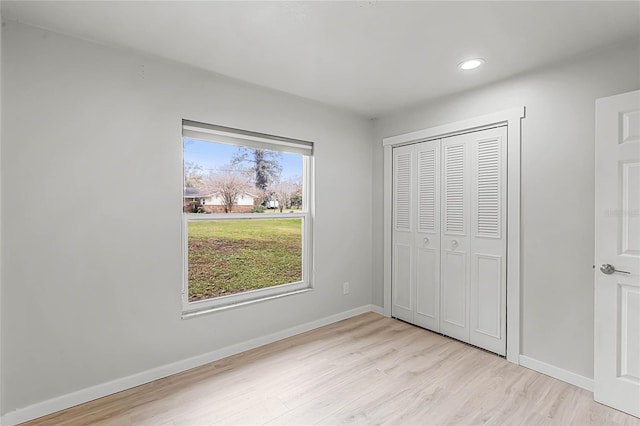 unfurnished bedroom with a closet, recessed lighting, wood finished floors, and baseboards