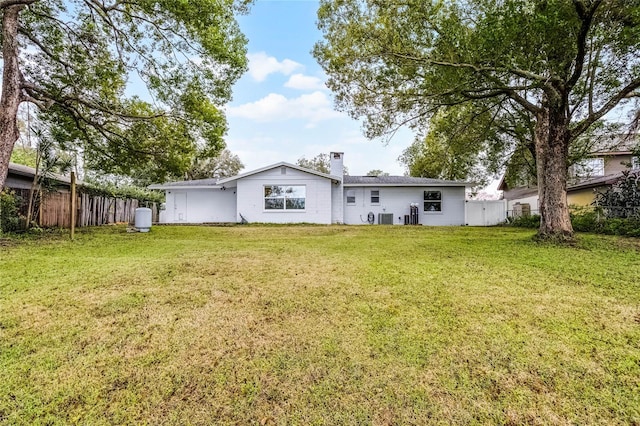 rear view of property with a yard, a chimney, and fence