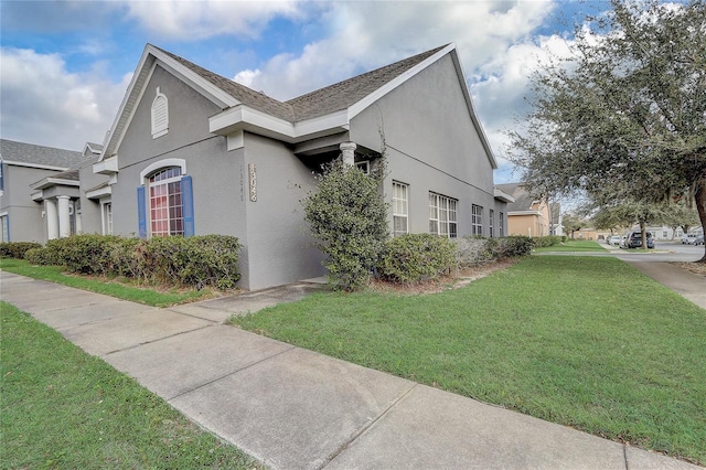 view of side of home with a lawn and stucco siding